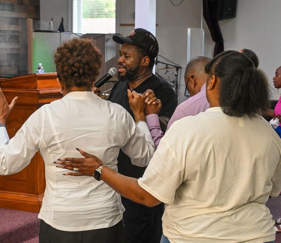 People standing close together with hands on one another's backs, praying.
